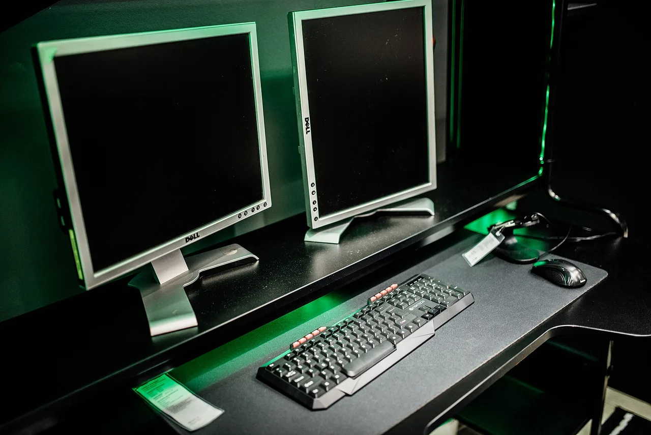 Игровое рабочее место с двумя мониторами: механическая клавиатура с подсветкой и мышь на столе крупным планом